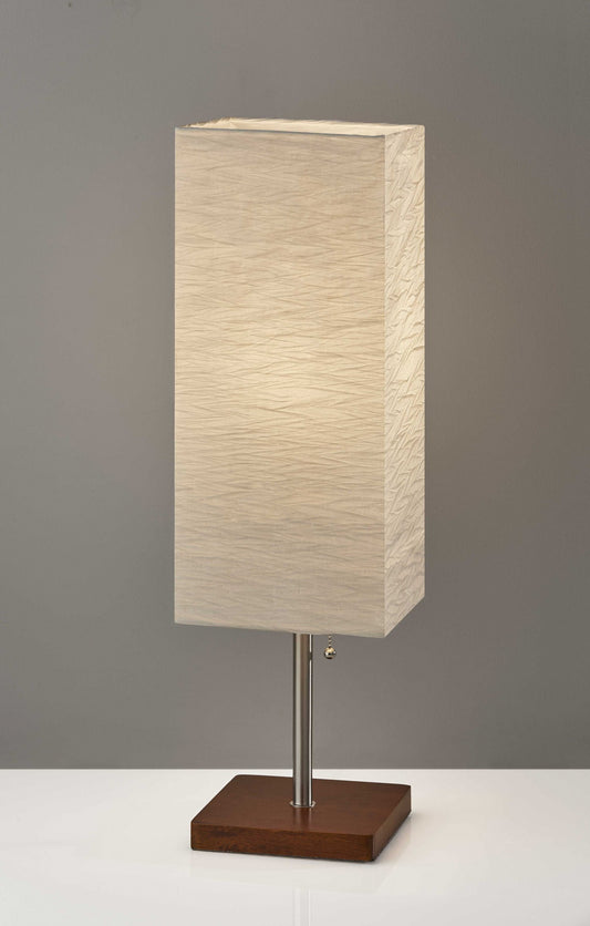 Table lamp with a rectangular beige shade on a wooden base against a gray background