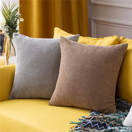 Yellow sofa with patterned cushions and a decorative blanket in a home setting.