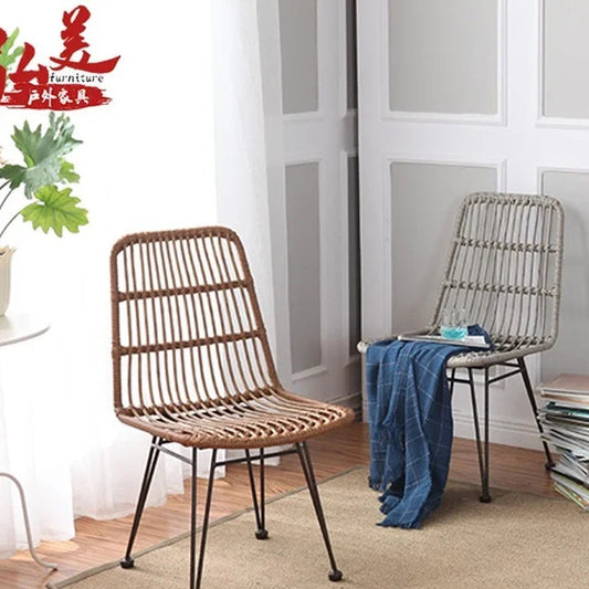 Two wicker chairs in a room with a plant and books.
