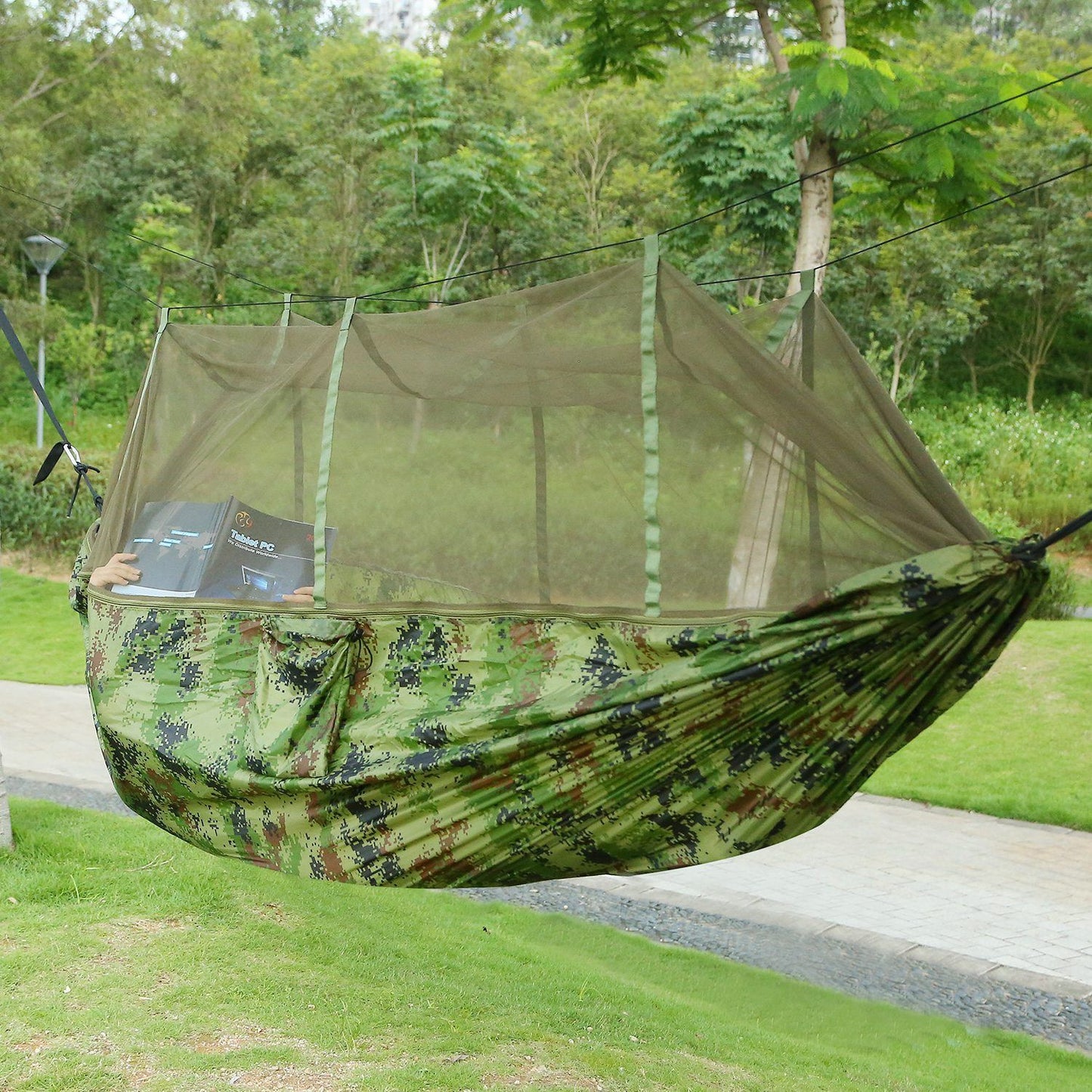 Double camping hammock with mosquito net set up between trees
