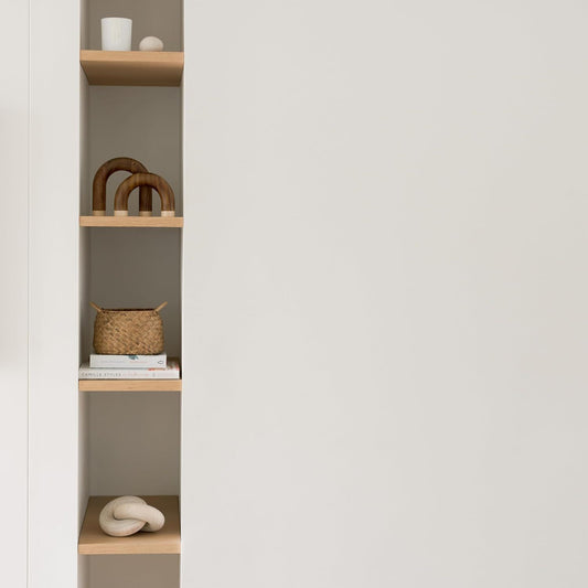 Shelving unit with wooden shelves and decorative items against a plain wall.