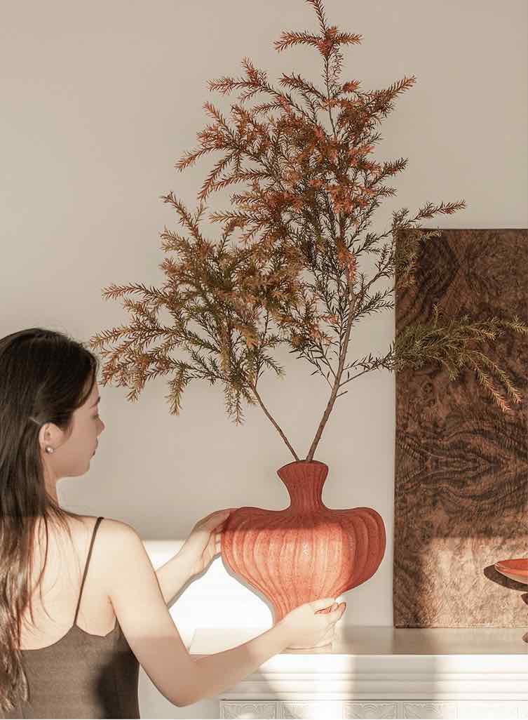 Artisan red pottery as bold shelf decor against neutral walls