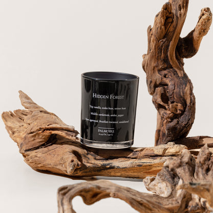 Black candle labeled 'Hidden Forest' on a wooden surface