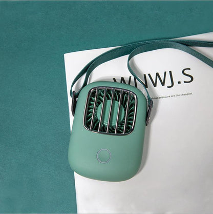 Green handheld fan on a magazine with a teal background