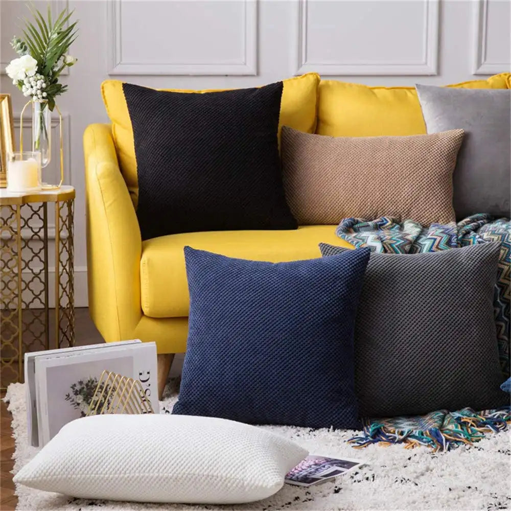Yellow sofa with colorful pillows and a side table in a living room setting
