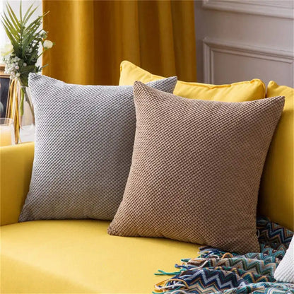 Yellow sofa with patterned cushions and a decorative blanket in a home setting.