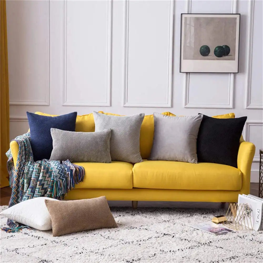 Yellow sectional sofa with colorful pillows in a living room setting.