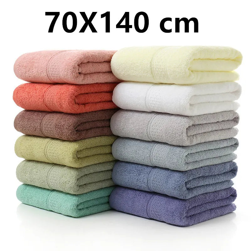 Stack of folded towels in various colors with dimensions 70X140 cm on a white background.