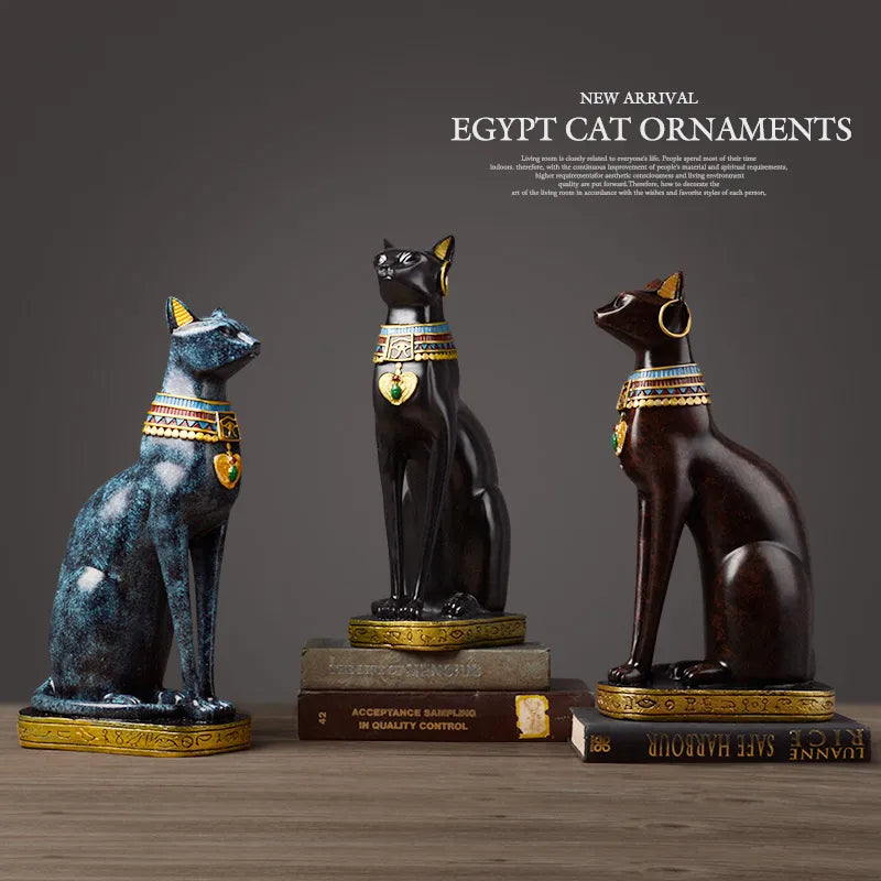Three Egyptian-style cat ornaments on a wooden surface with a dark background.