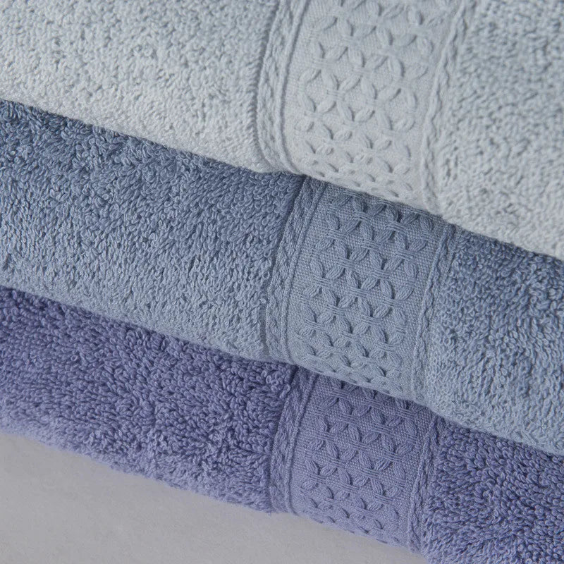 Stack of textured towels in various shades of blue on a light gray background