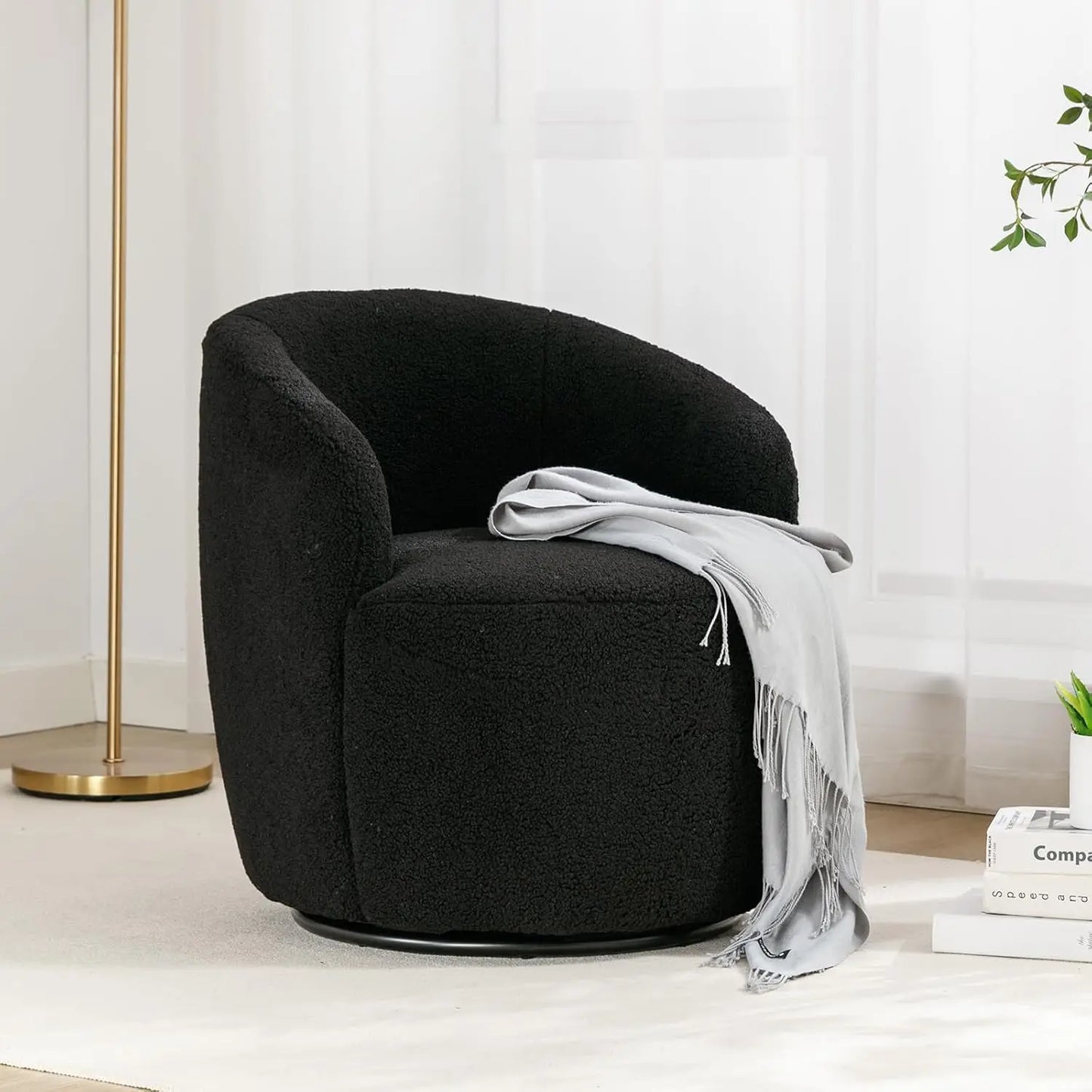 Black swivel chair with a gray blanket in a minimalistic room.