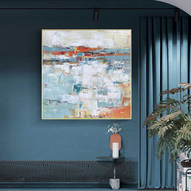 Abstract painting on a teal wall with a plant and small table below.