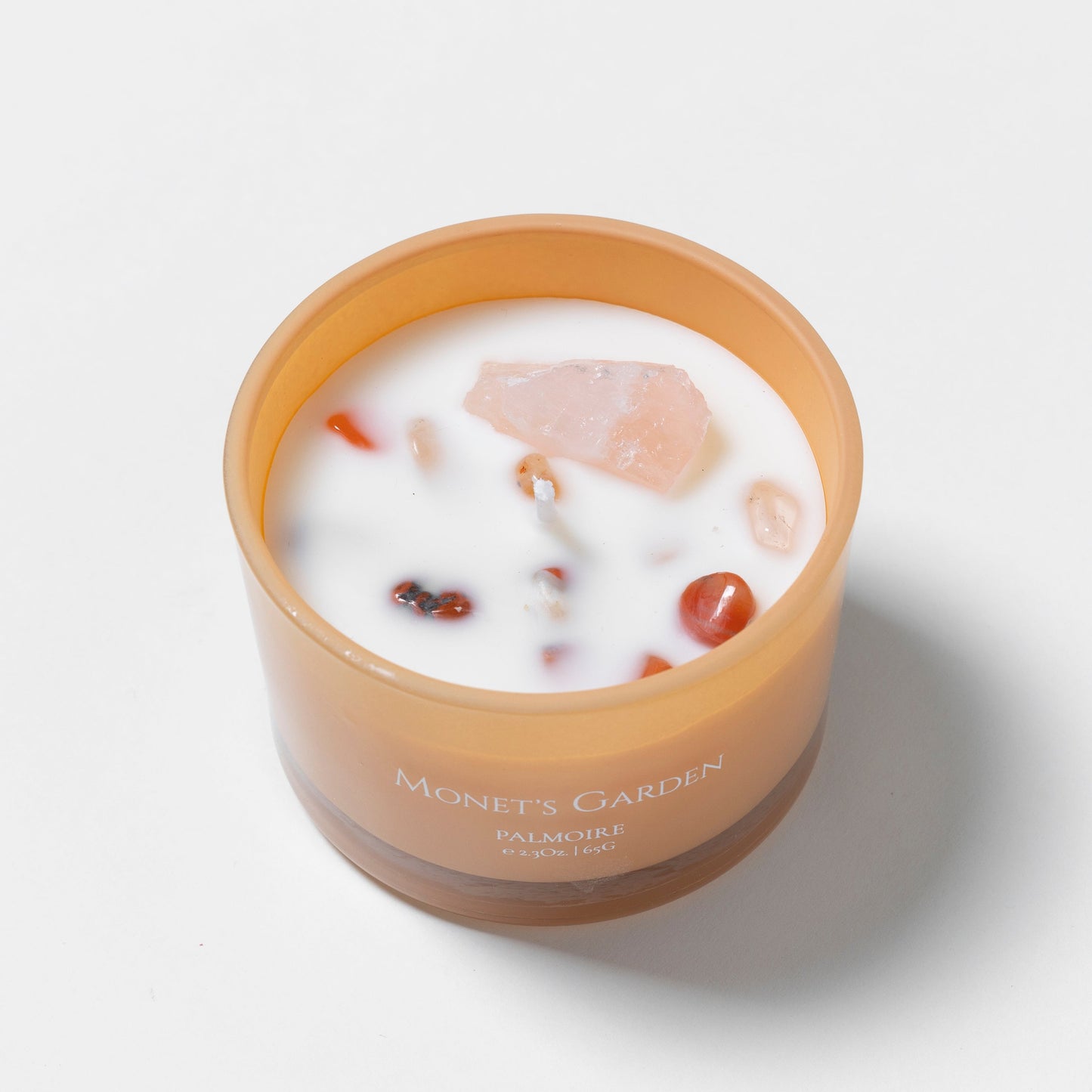 Candle in a brown jar with visible ingredients on a white background
