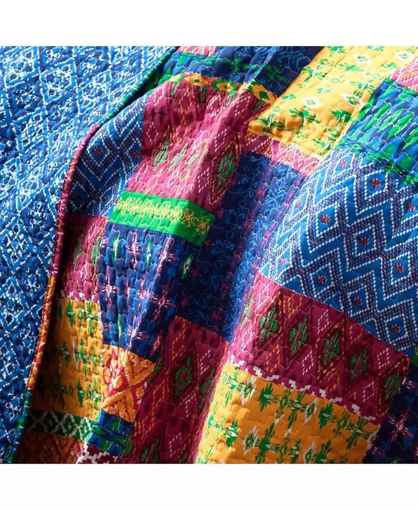 A close-up of a colorful patchwork quilt with geometric and floral patterns in blue, magenta, yellow, and green.