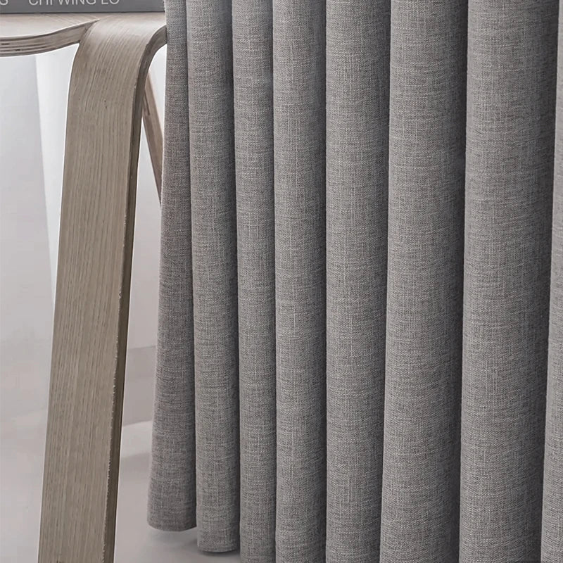 Close-up of gray curtains with a wooden chair in the background