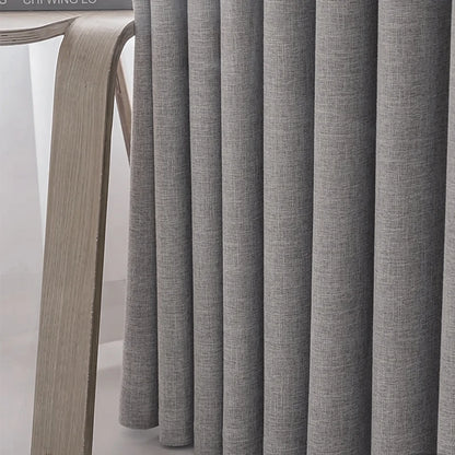 Close-up of gray curtains with a wooden chair in the background