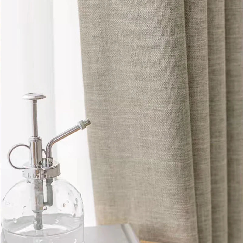 Clear glass bottle with silver pump against a beige curtain background