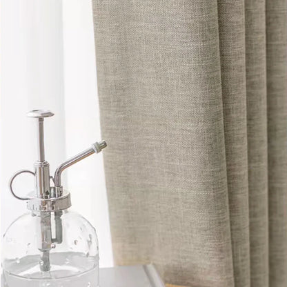 Clear glass bottle with silver pump against a beige curtain background