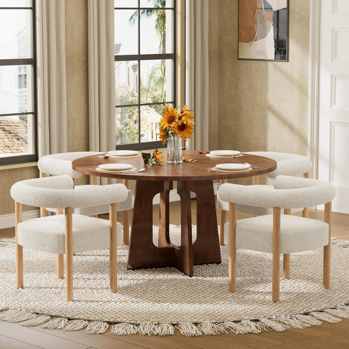 A round wooden dining table with a sculptural pedestal base, surrounded by six upholstered dining chairs with light wood legs, set on a woven area rug in a bright dining room.