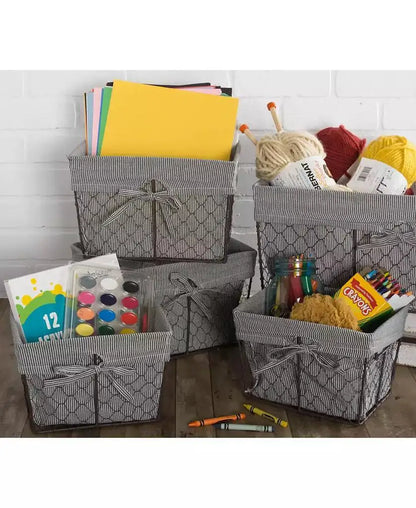 Lined wire storage baskets holding craft paper, yarn, paints, crayons, and art supplies.