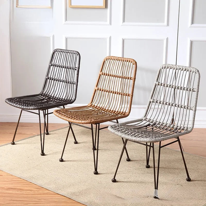 Three wicker chairs in black, brown, and gray on a wooden floor.