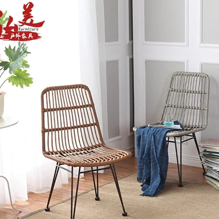 Two wicker chairs in a room with a plant and books.