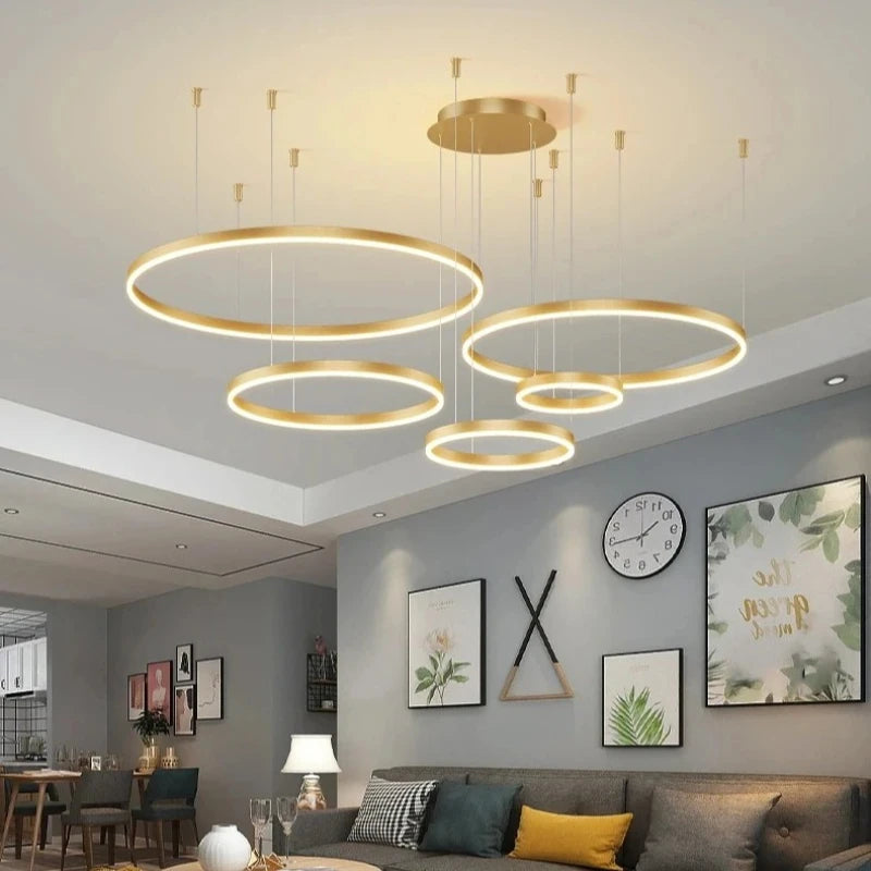 Modern living room with gold circular pendant lights, gray walls, and decorative elements.