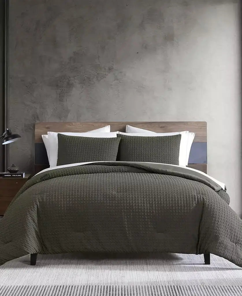 Dark green embossed houndstooth duvet cover and matching shams styled on a modern wood bed with white sheets.