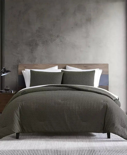 Dark green embossed houndstooth duvet cover and matching shams styled on a modern wood bed with white sheets.