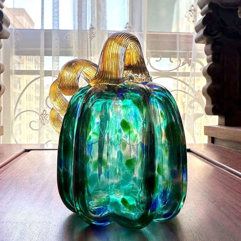 Glass pumpkin with a gold stem on a wooden surface