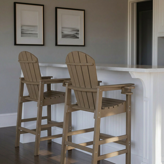 Two wooden bar stools in front of a white countertop with framed pictures on the wall.