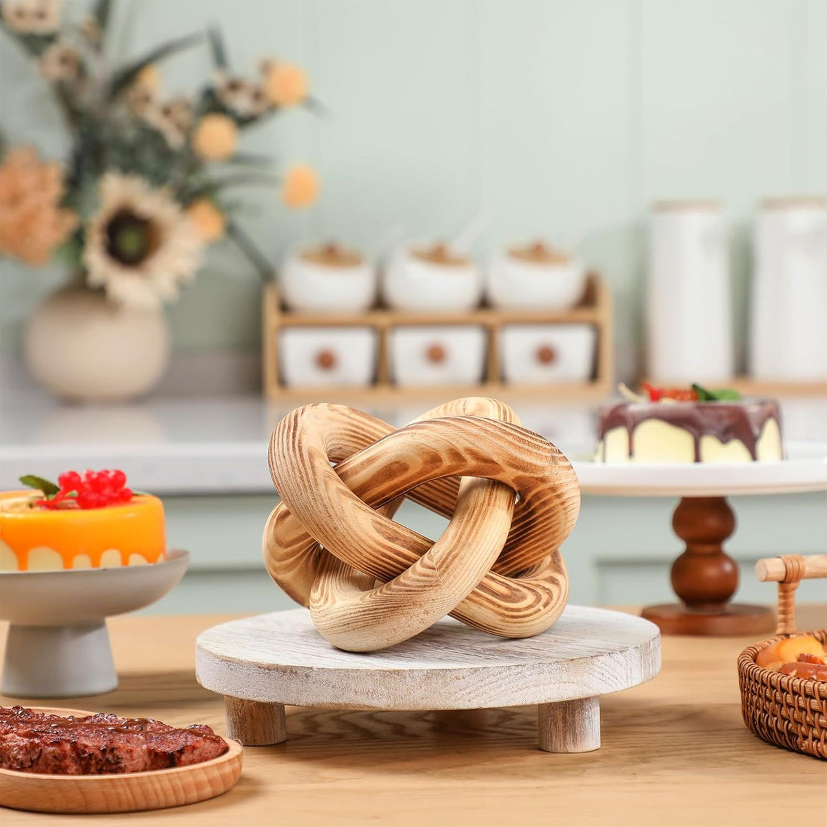 Wooden knot sculpture on a marble base with a blurred background of desserts and decor.