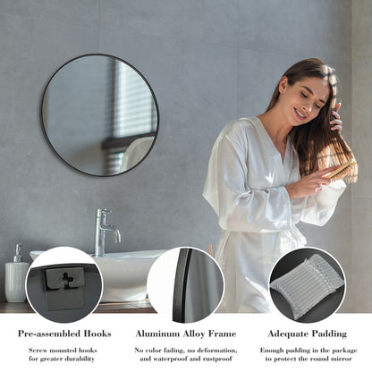 Woman in a bathroom with a round mirror, sink, and faucet.