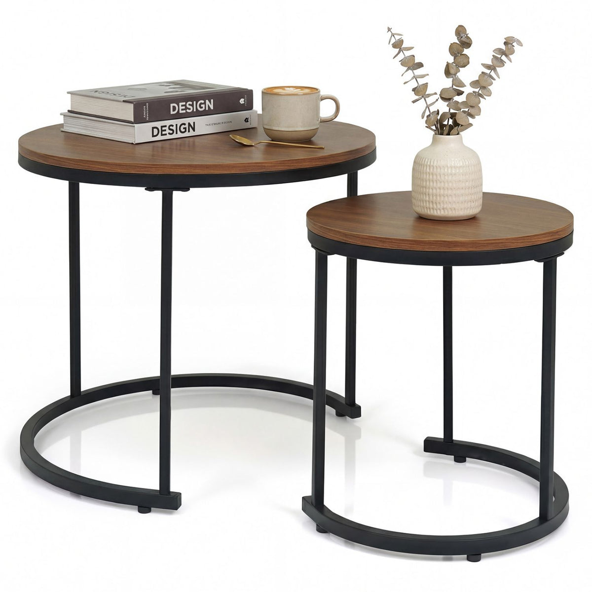 Set of two wooden side tables with black metal legs, one with books and a cup, the other with a vase and plant.
