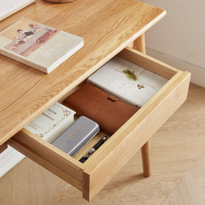Wooden desk with open drawer containing stationery items on a wooden floor.