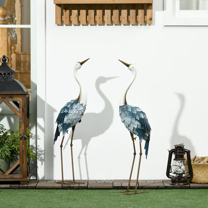 Two decorative cranes on a patio with lanterns and plants.