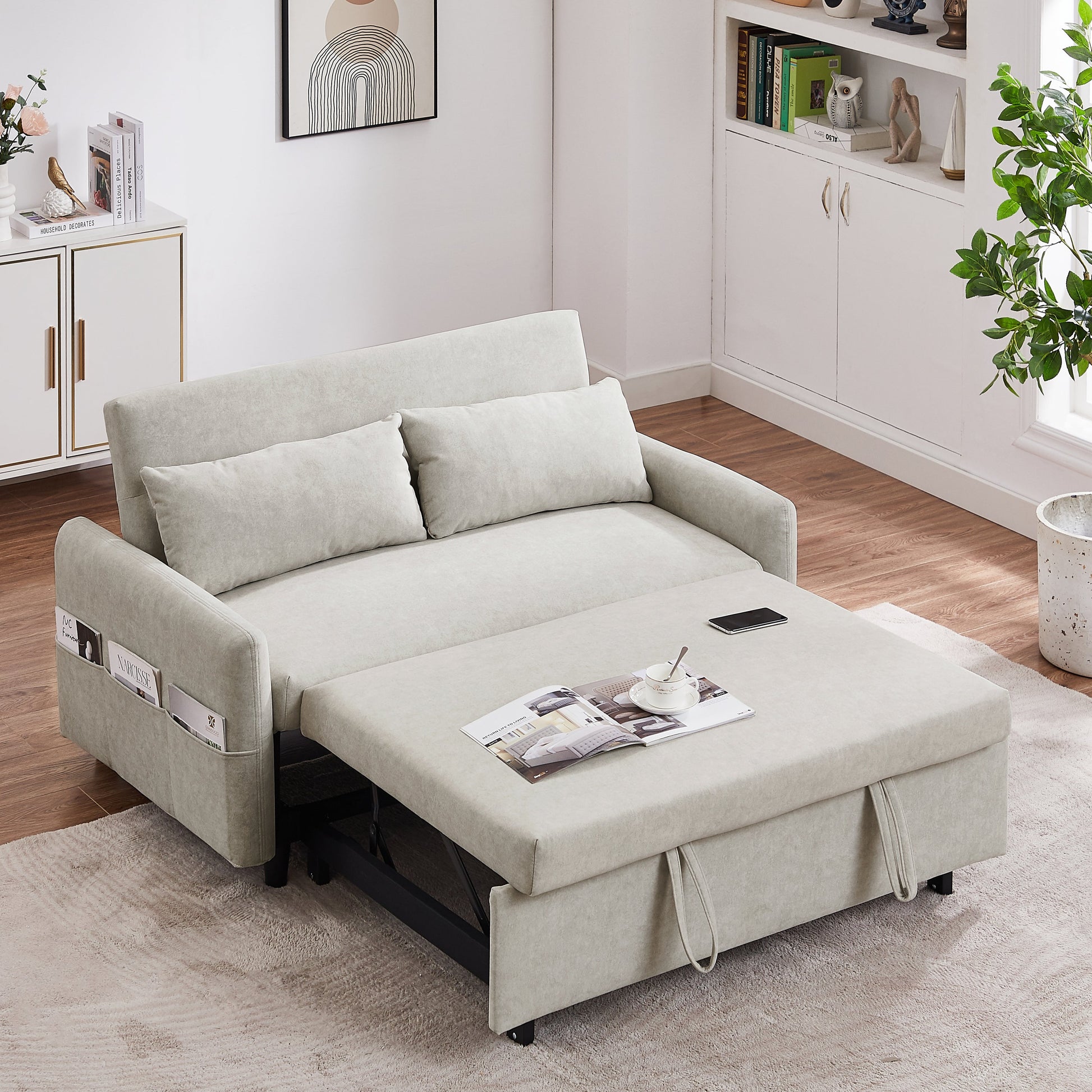 Beige sofa bed in a living room setting with magazines and a phone on it.