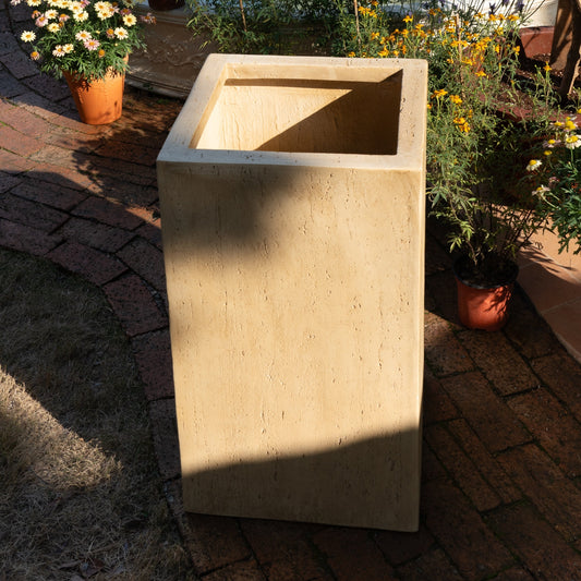Beige rectangular planter on a patio with potted plants around