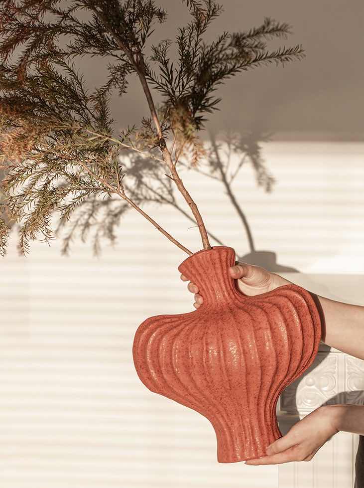 Artisan red pottery as bold shelf decor against neutral walls